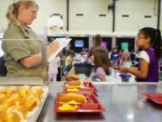 Share volunteer Kari Barnes marks off the daily meal count as children pass through the lunch line at Silver Star Elementary.