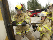 Clark County Fire and Rescue firefighters Zach Johnson, left, and Pavel Zabolotskiy use a Halligan tool to force entry through a door during a training exercise Thursday.