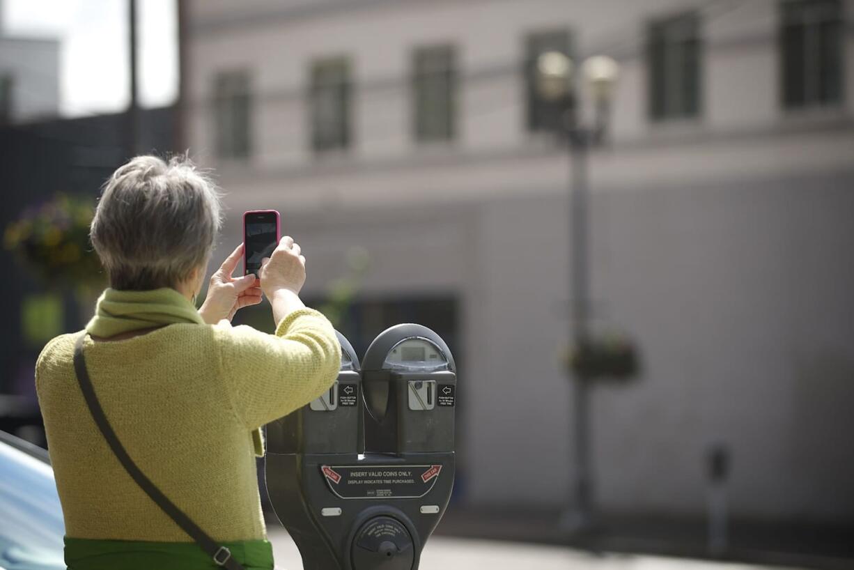 Rene Neff, a city councilor, business owner and Main Street association member in Langley, photographs a building at Seventh and Main streets during a tour of downtown Vancouver. A large awning was recently removed from the building, exposing more of the historic structure's facade.