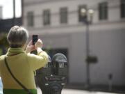 Rene Neff, a city councilor, business owner and Main Street association member in Langley, photographs a building at Seventh and Main streets during a tour of downtown Vancouver. A large awning was recently removed from the building, exposing more of the historic structure's facade.