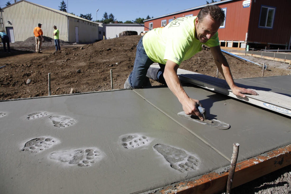 Ezechel Rusnak of Team Construction stamps animal footprints into fresh concrete at the special &quot;playscape&quot; now being built at the Cardinal Preschool at St. Joseph Catholic School.