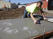 Ezechel Rusnak of Team Construction stamps animal footprints into fresh concrete at the special &quot;playscape&quot; now being built at the Cardinal Preschool at St. Joseph Catholic School.