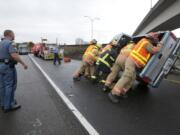 Washington State Patrol Sgt. Joel Gordon watches as Vancouver firefighters push a truck upright at the scene of a rollover accident on the ramp to state Highway 14 from northbound Interstate 5 shortly after 3 p.m.