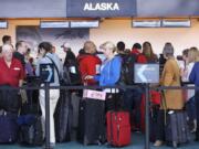 Commuters wait in long lines to check in at Alaska Airlines on Monday at Portland International Airport.