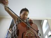 Akemi Noll, who was diagnosed with early-onset Parkinson's six years ago, practices the cello at her east Vancouver home Wednesday.