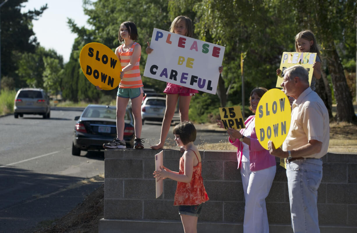 Paul Houge, right, along with other neighborhood residents, urge drivers to slow down on McGillivray Boulevard on a recent Thursday afternoon in August.