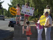 Paul Houge, right, along with other neighborhood residents, urge drivers to slow down on McGillivray Boulevard on a recent Thursday afternoon in August.