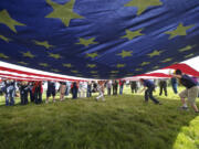 Cub Scouts, Boy Scouts, Girl Scouts and National Park Service staff members display a large flag during the Pledge of Allegiance at the annual Flag Day ceremony Thursday at the Parade Ground.