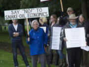 Edie Cotton, center in blue, of Vancouver protests outside Hudson's Bay High School before the start of a public information meeting about an oil terminal proposed at the Port of Vancouver.