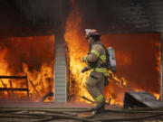 Assistant Fire Chief Shawn Newberry walks by a burning garage last week at the first of two training fires.