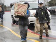 Dante Breeding, 5, left, and Gabriel Breeding, 8, haul bags of food from their van to the Walk &amp; Knock drop-off site at Orchards Elementary School. They were among about 3,700 Clark County residents who volunteered for the annual event Saturday.