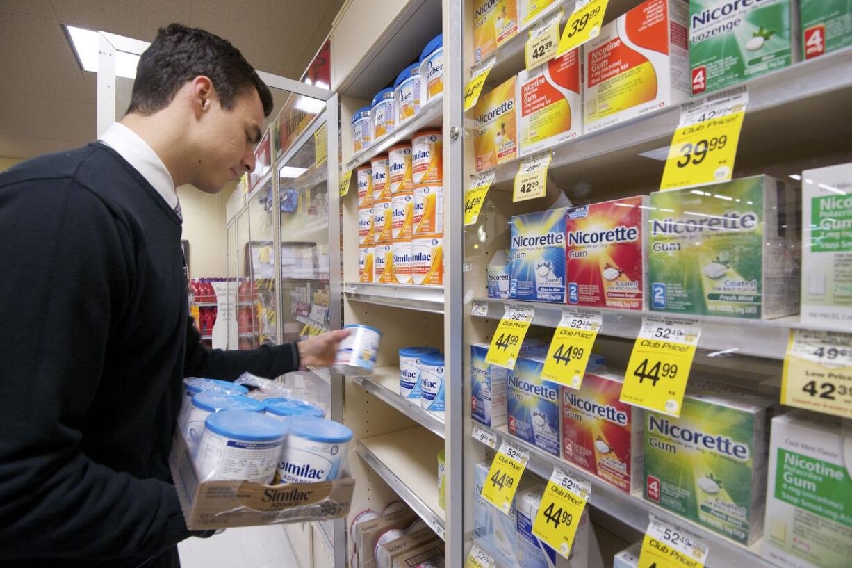 Matt Brown, a supervisor at the Salmon Creek Safeway, inspects infant formula in a locked case Tuesday.