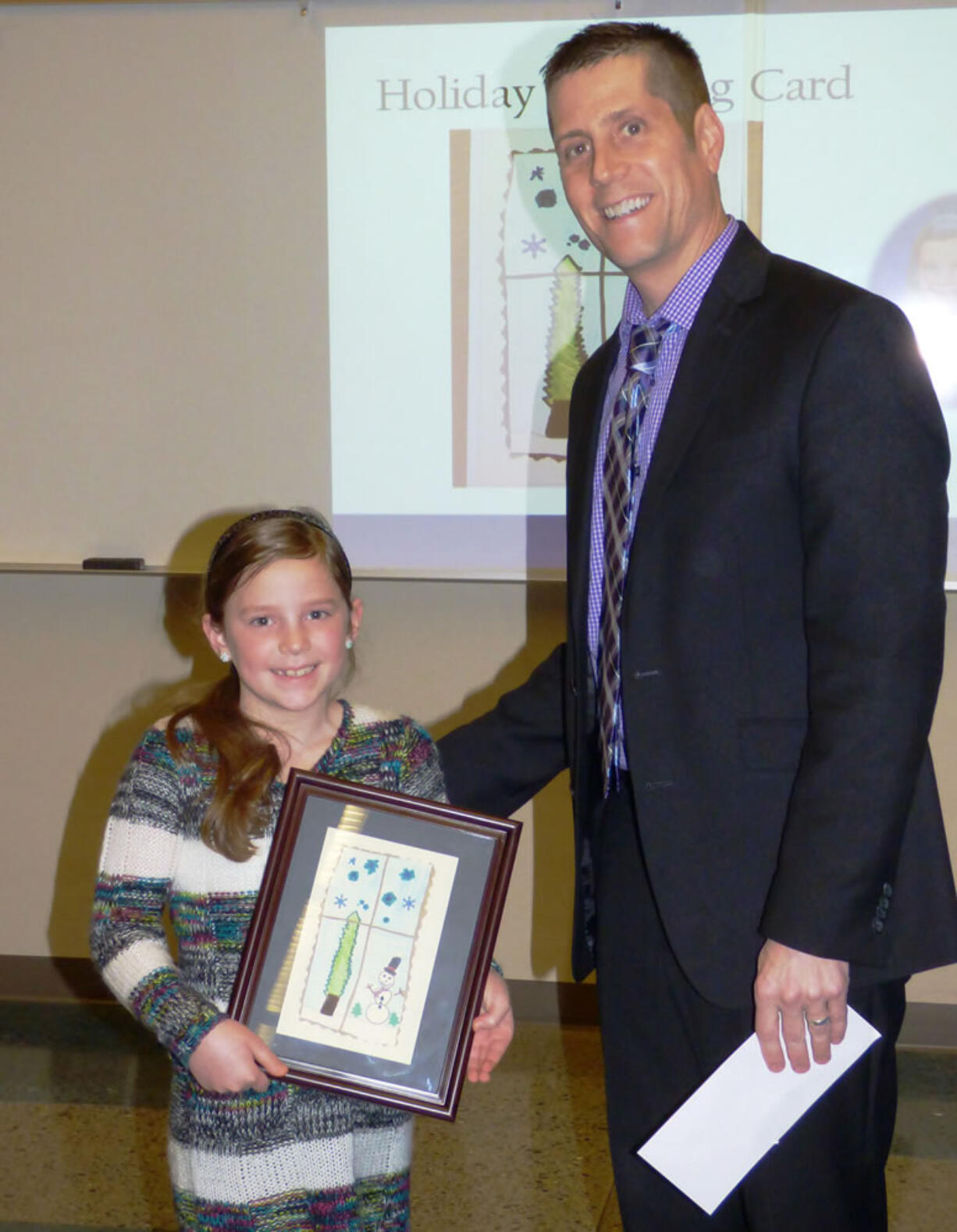 Ridgefield: South Ridge Elementary School second-grader Emma Waddle and Ridgefield School District Superintendent Nathan McCann celebrating Emma&#039;s win the district&#039;s annual Holiday Greeting Card Contest.