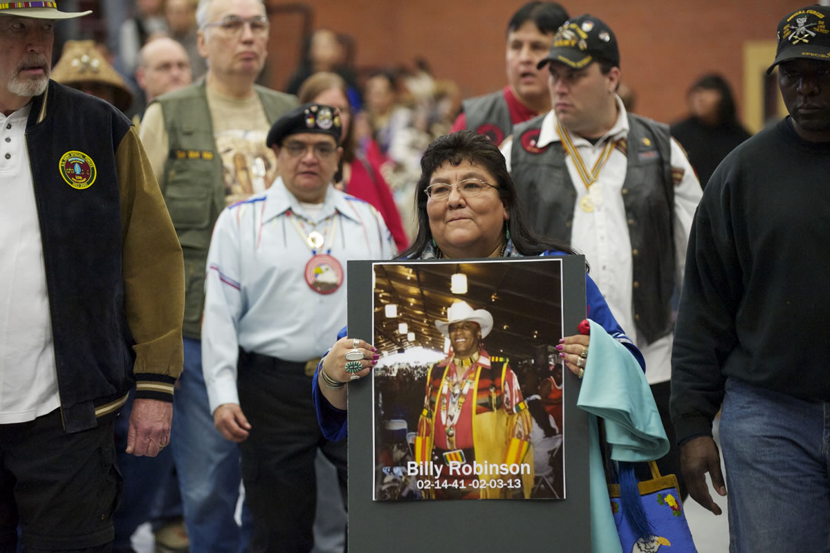 Nanette Robinson of Camas carries a photo of her husband, Billy Robinson, who died Feb. 3, as she marches Saturday with other veterans.