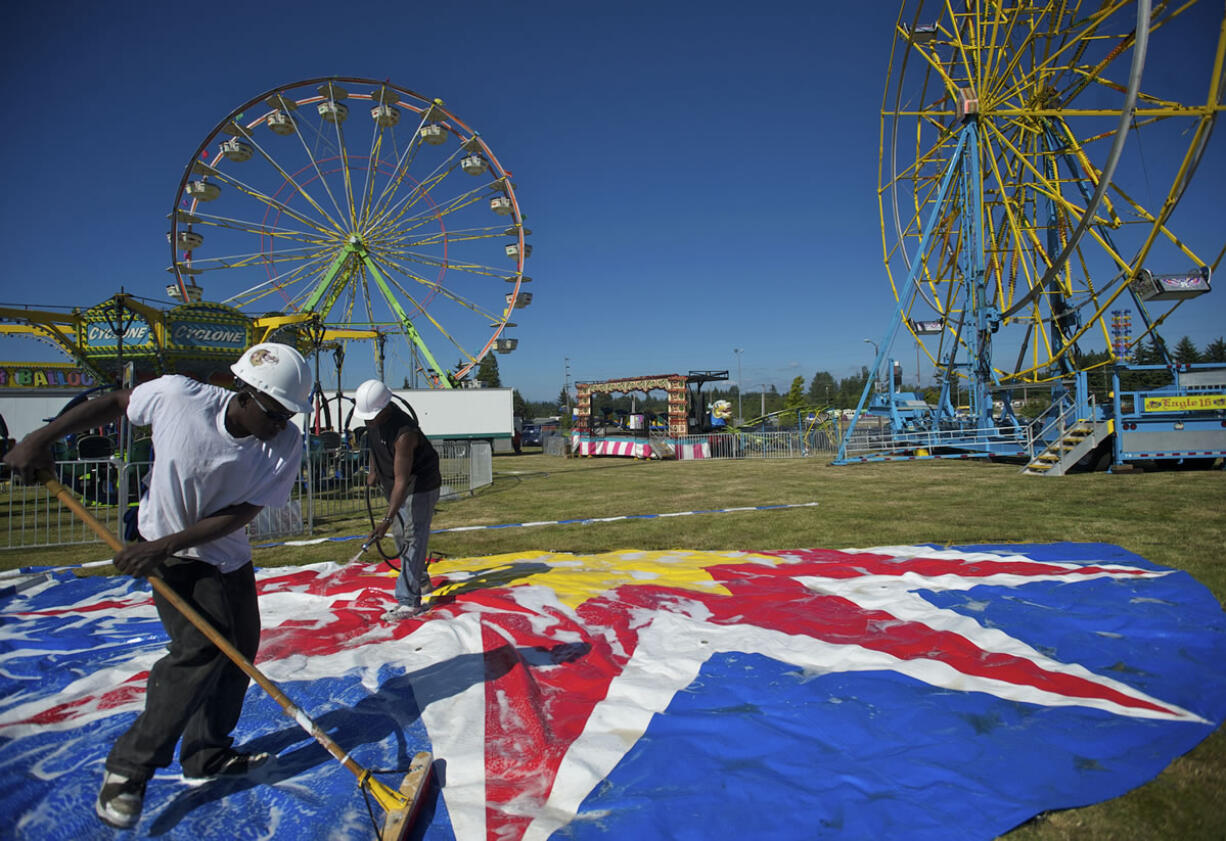 Butler Amusements carnival workers Andrew Jackson, foreground, 44, and Roosevelt Conley, 39, wash the top for the small carousel in preparation for the Clark County Fair.