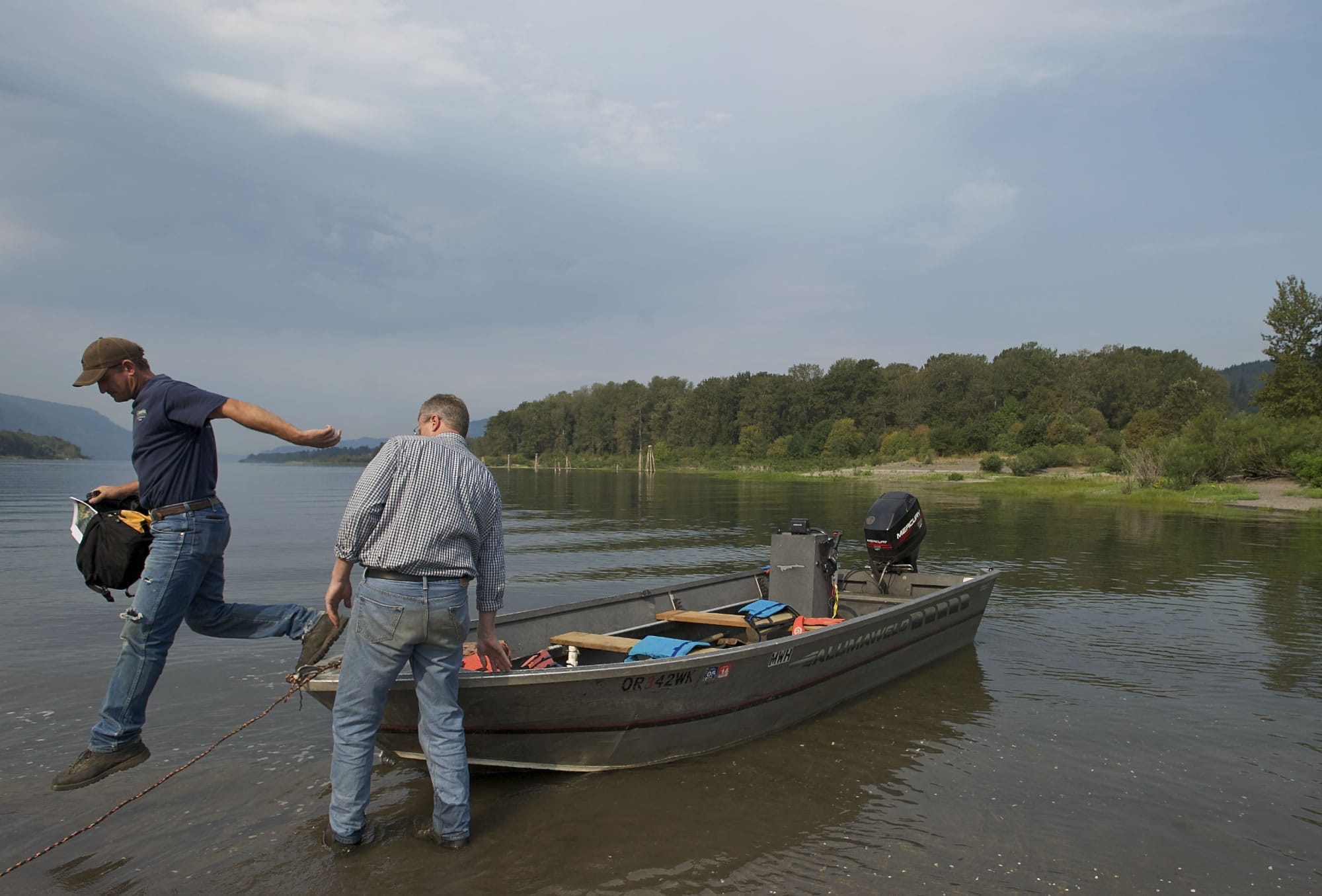 Columbia Land Trust stewardship director Ian Sinks steadies a boat as stewardship lead Dan Friesz jumps to shore at Pierce Island this week.