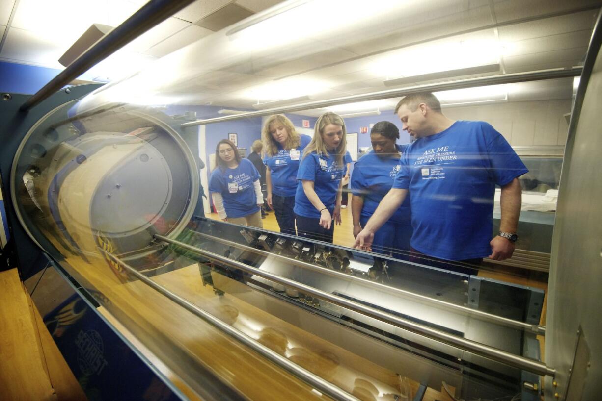 Joyce Garcia, from left, Tricia Walsh, Amy Lara, Robin Jones and Billy Kealiher -- all staff members with PeaceHealth Southwest Medical Center Specialty Clinics -- take a closer look at a new hyperbaric oxygen chamber delivered Tuesday morning.