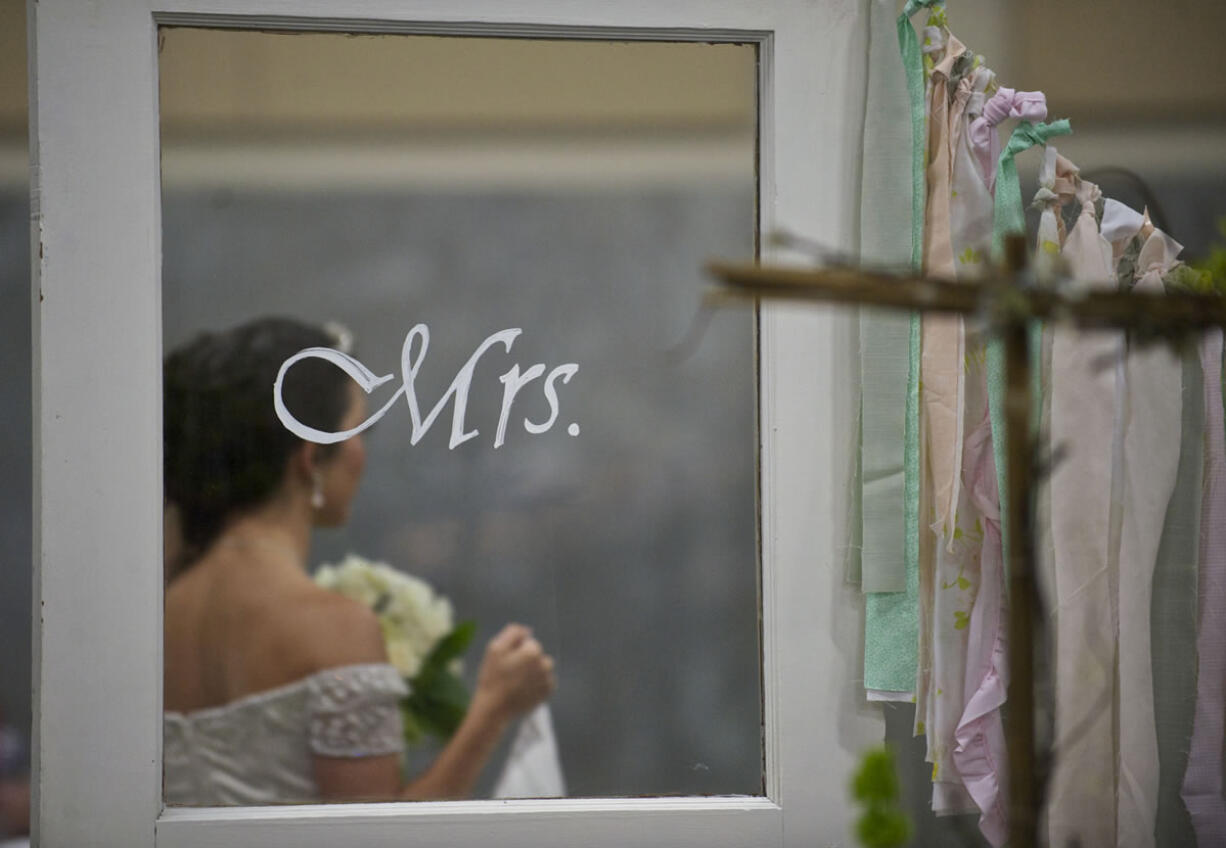 Jessica Hobbs-Steele, 19, of Camas, modeling for Gala Gown of Vancouver, passes a display at Sunday's wedding show.