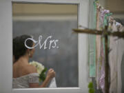 Jessica Hobbs-Steele, 19, of Camas, modeling for Gala Gown of Vancouver, passes a display at Sunday's wedding show.