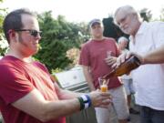 Carter Park resident Gary Kokstis pours a glass of home-brewed beer for neighbor Jerrad Isch during a gathering of the informal 29th Street Brewers Guild in Kokstis' backyard garden.