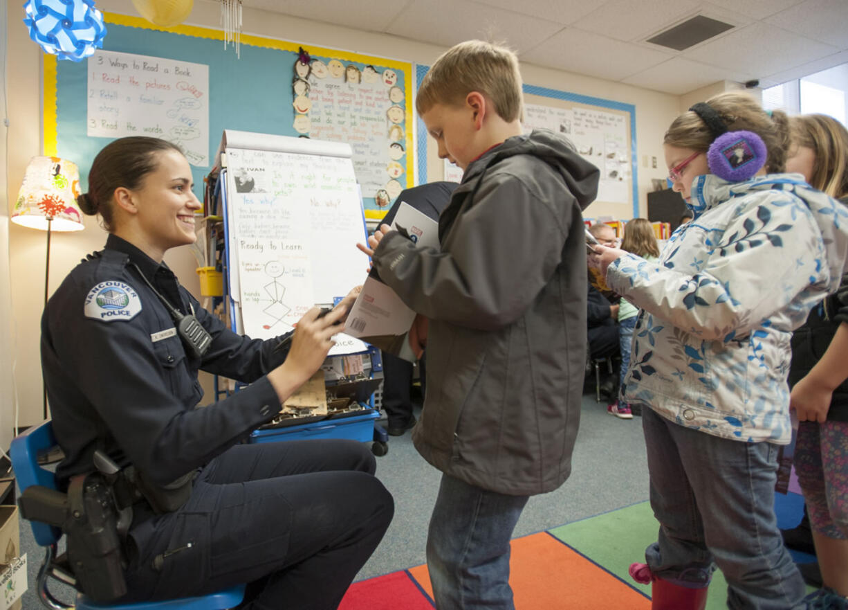 Vancouver police Officer Katie Endresen autographs books for second-graders at Mill Plain Elementary School. Between October and June, the Police Activities League goes into schools and promotes reading while trying to improve relationships with police.