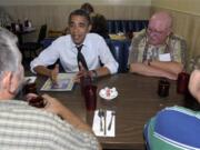 President Barack Obama visits with military veterans Dean Dilley, left, Mark Peterson, background, right, and Thomas Foeller, right, during a stop to the Gateway Breakfast House in Portland today.