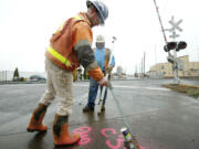 John Tuininga, left, and Wilfrano Zuniga, of Nutter Corp., mark sections of asphalt Monday in Vancouver.