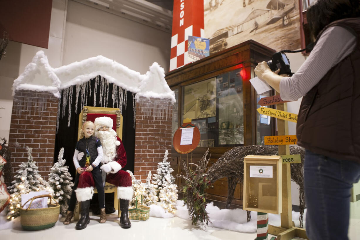 Tina Stokes takes a picture of her daughter, Calista Stokes, 6, with Santa on Saturday at the Festival of Trees at Pearson Air Museum.