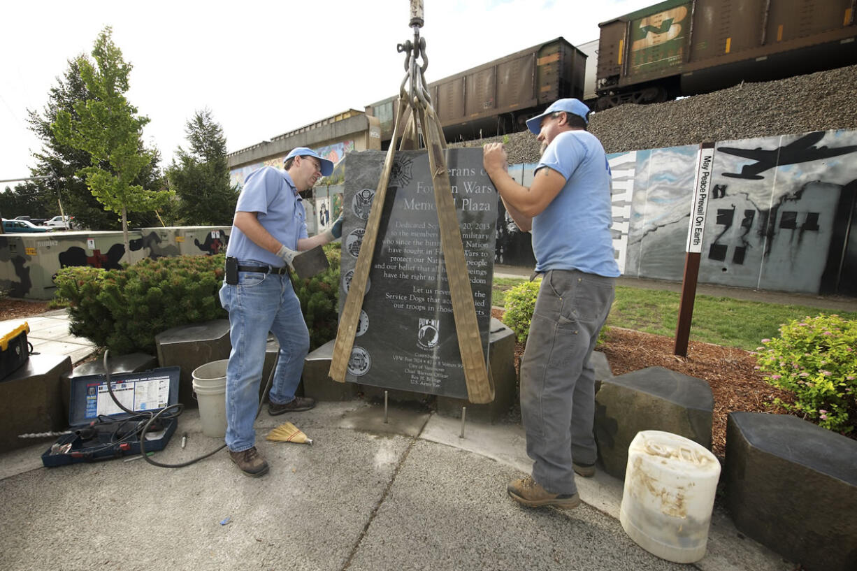 Joey Fuerstenberg, left, and Kyle Cochran of Vancouver Granite Works move a black granite monument into place Wednesday morning at the Veterans of Foreign Wars Memorial Plaza in Vancouver.