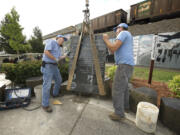 Joey Fuerstenberg, left, and Kyle Cochran of Vancouver Granite Works move a black granite monument into place Wednesday morning at the Veterans of Foreign Wars Memorial Plaza in Vancouver.