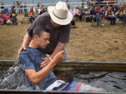 Using a horse trough, Larry Cutler baptizes Daniel Sage at the conclusion of the camp at the Vancouver Saddle Club on Aug. 15.