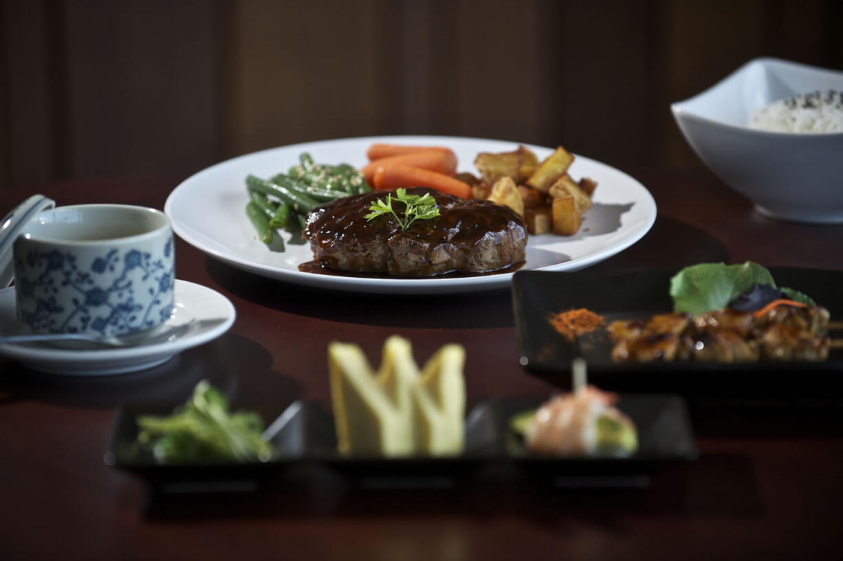 A six-course dinner at Koji includes a dish of Chawan Mushi, left; seaweed salad, Tamagoyaki, shrimp and asparagus, front; Wagyu beef hamburg steak, back center, with green beans, carrots and potatoes; Yakitori, second from right, and rice.