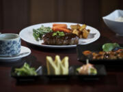 A six-course dinner at Koji includes a dish of Chawan Mushi, left; seaweed salad, Tamagoyaki, shrimp and asparagus, front; Wagyu beef hamburg steak, back center, with green beans, carrots and potatoes; Yakitori, second from right, and rice.