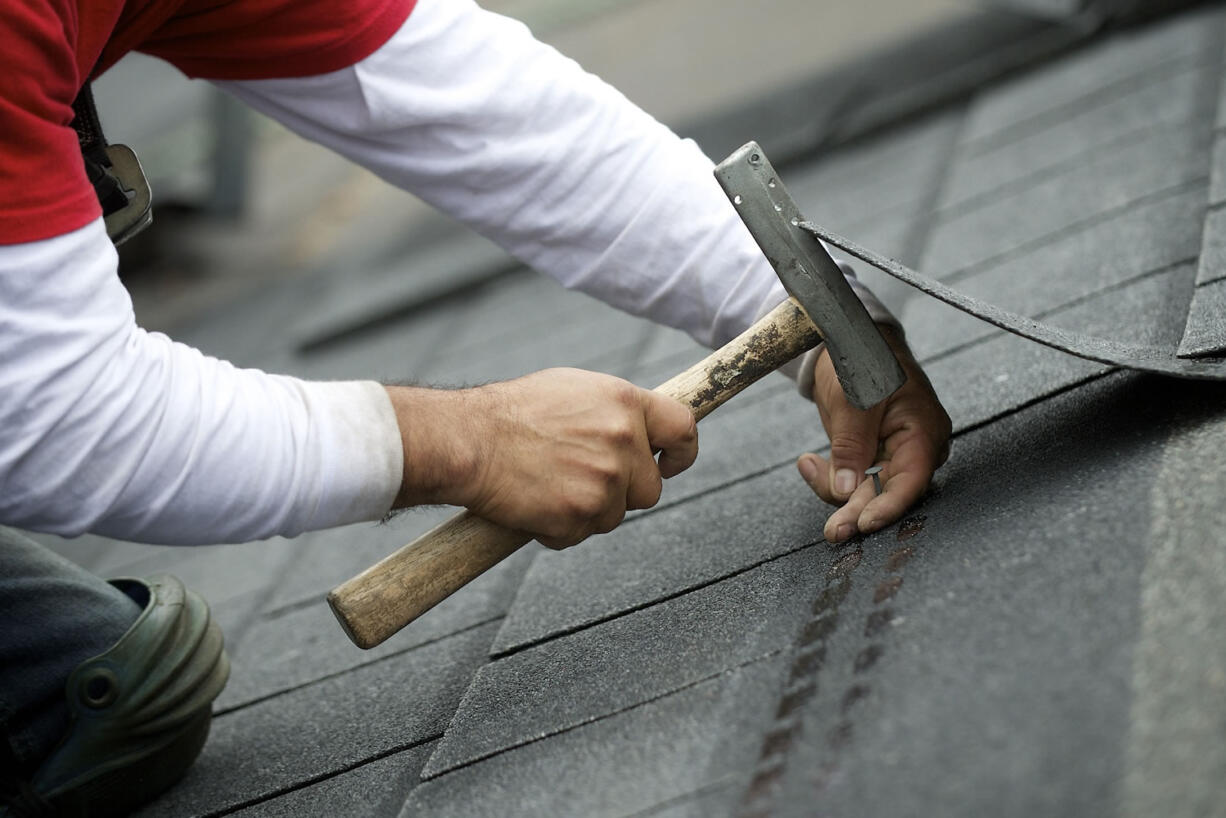 Pedro Rosales-Ruiz, with Weatherguard Inc. of Longview, puts another nail in a shingle Friday on the roof of an Officers Row house.