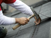 Pedro Rosales-Ruiz, with Weatherguard Inc. of Longview, puts another nail in a shingle Friday on the roof of an Officers Row house.