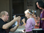 Dave Lemberg, owner of Dave's Killer Magic Shop, shows Taryn Larsen, 9, and her mother, Michele Larsen, a trick during a May 11 workshop in front of his Vancouver shop.