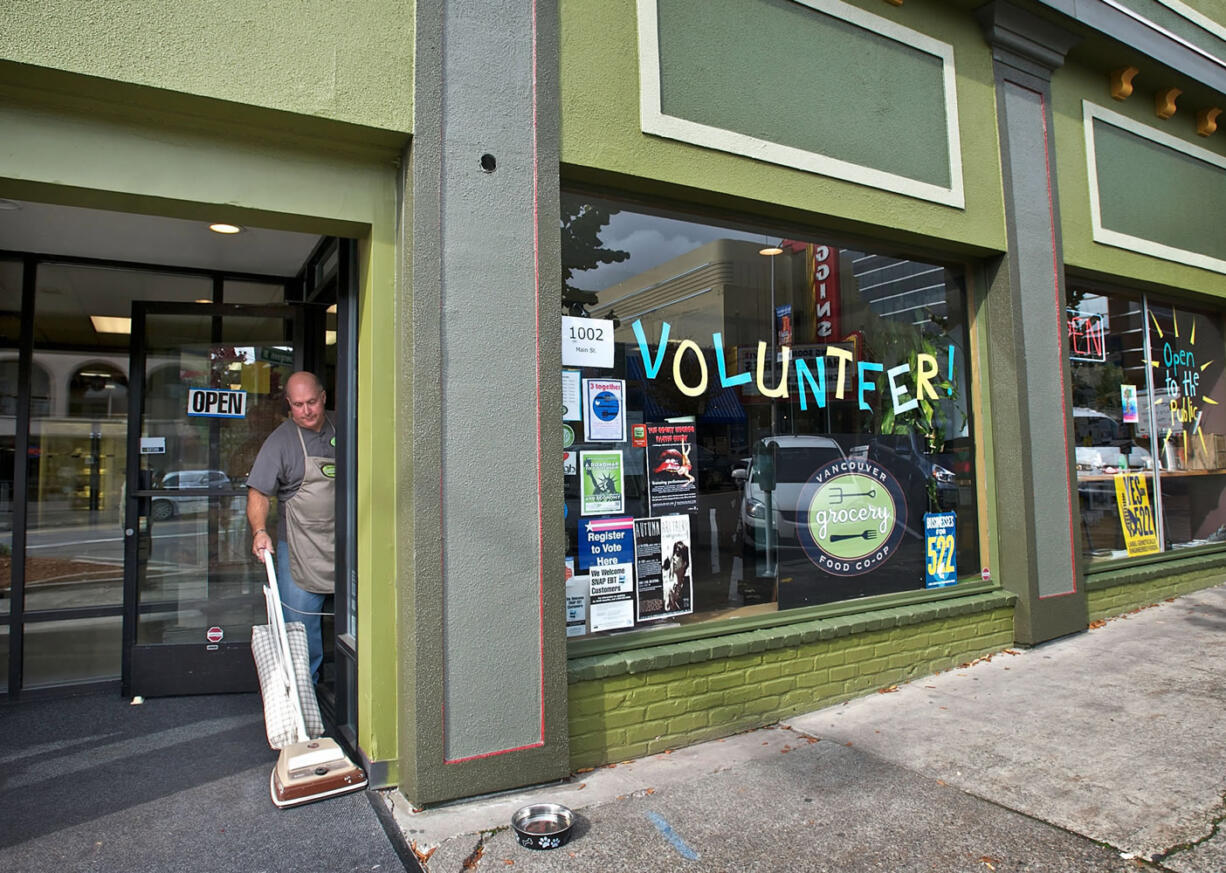 Vancouver Food Co-op volunteer Mark Henrichsen vacuums the entrance of the Main Street grocery on Friday. The sign in the window says it all: the co-op needs lots more volunteer energy to stay alive, according to board President Kirk Wright.