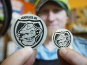 Wade Leckie, owner of Bad Monkey Bikes, holds specially designed and difficult to remove monkey shield stickers Friday at his shop in Vancouver.