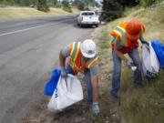 John Enslow, left, helps Ecology Youth Corps member Jake Jonas, 17, pick up trash along Interstate 5. Enslow visits different youth corps crews once a week to make sure they adhere to guidelines and safety procedures. Below: Alexandria Williams, 15, picks up trash along Interstate 5 on Monday.