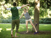 Cullen, left, and Lauren Reynolds, 19, of Vancouver, walk toward each other on the slackline, high-five and jump off. The two set up a slackline over water at a dock in Camas on Aug.