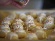 Dena Corso adds sprinkles to a batch of cuccidati cookies at the Vancouver home of Paul and Judy Corso on Saturday.