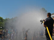 Paramedic-firefighter Chris Richardson of the Camas-Washougal Fire Department sprays kids at the Camas Days bathtub races on Saturday.