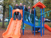 Camas: Enjoying the new Forest Home Park playground despite the rain are Parks Foundation executive director Cheri Martin, on slide, and, from left, Camas Mayor Scott Higgins, Scott Campbell of Waste Connections, Alex Williams of Northwest Playground Equipment, Brent Ericksen of the Camas Parks &amp; Recreation Commission and Melissa Smith of the Camas City Council.