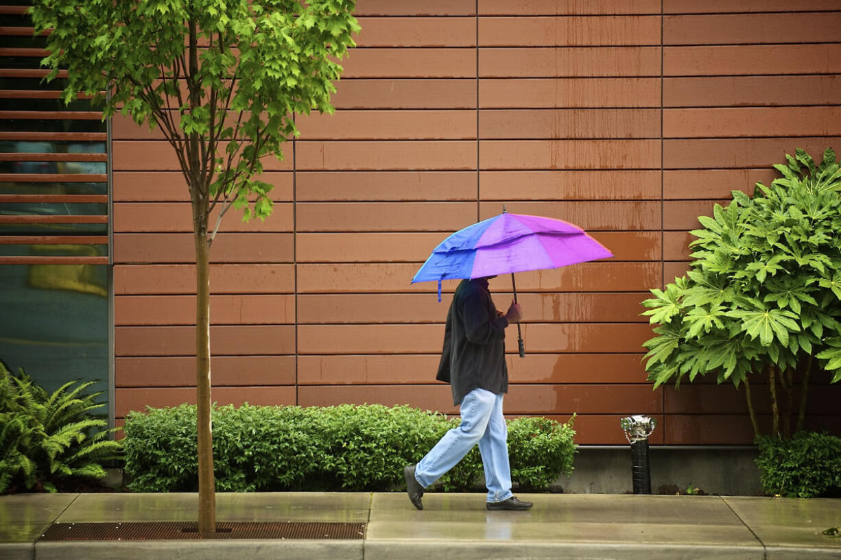 A pedestrian walks along East Evergreen Boulevard protected by a colorful umbrella as record rainfall ended Friday.