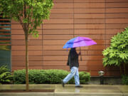 A pedestrian walks along East Evergreen Boulevard protected by a colorful umbrella as record rainfall ended Friday.