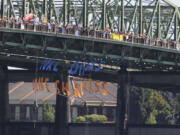 Three protesters on ropes lower a banner under the bridge supports as hundreds of protesters cross the Columbia River in support of an amphibious demonstration at the Interstate bridge against proposed fossil fuel facilities in the Northwest, in Vancouver, Wa., Saturday July 27, 2013.