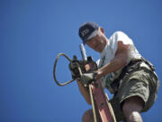 At left, Rich Ullsmith of Camas hauls up a new assembly for the top of Pam McNamara's flagpole.