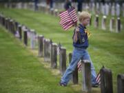 Ryan Nelson, 8, of Ridgefield, and other Cub Scouts from Pack 637 placed flags on the graves of veterans Thursday at the Post Cemetery.