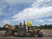 Aireanna Vanasse, 3, and Katrina Stanley, 24, drive the tractor as Brandon Jacobi, 25, and Nellie Vanasse, 21, plant a row of red cabbage at Gee Creek Farm outside Ridgefield last week.