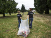 Woodland High School cheerleaders Justise Anderson, left, and Ally Baluta, 15, join a group of athletes helping to clean up the mess after the July 4th celebration at Fort Vancouver.